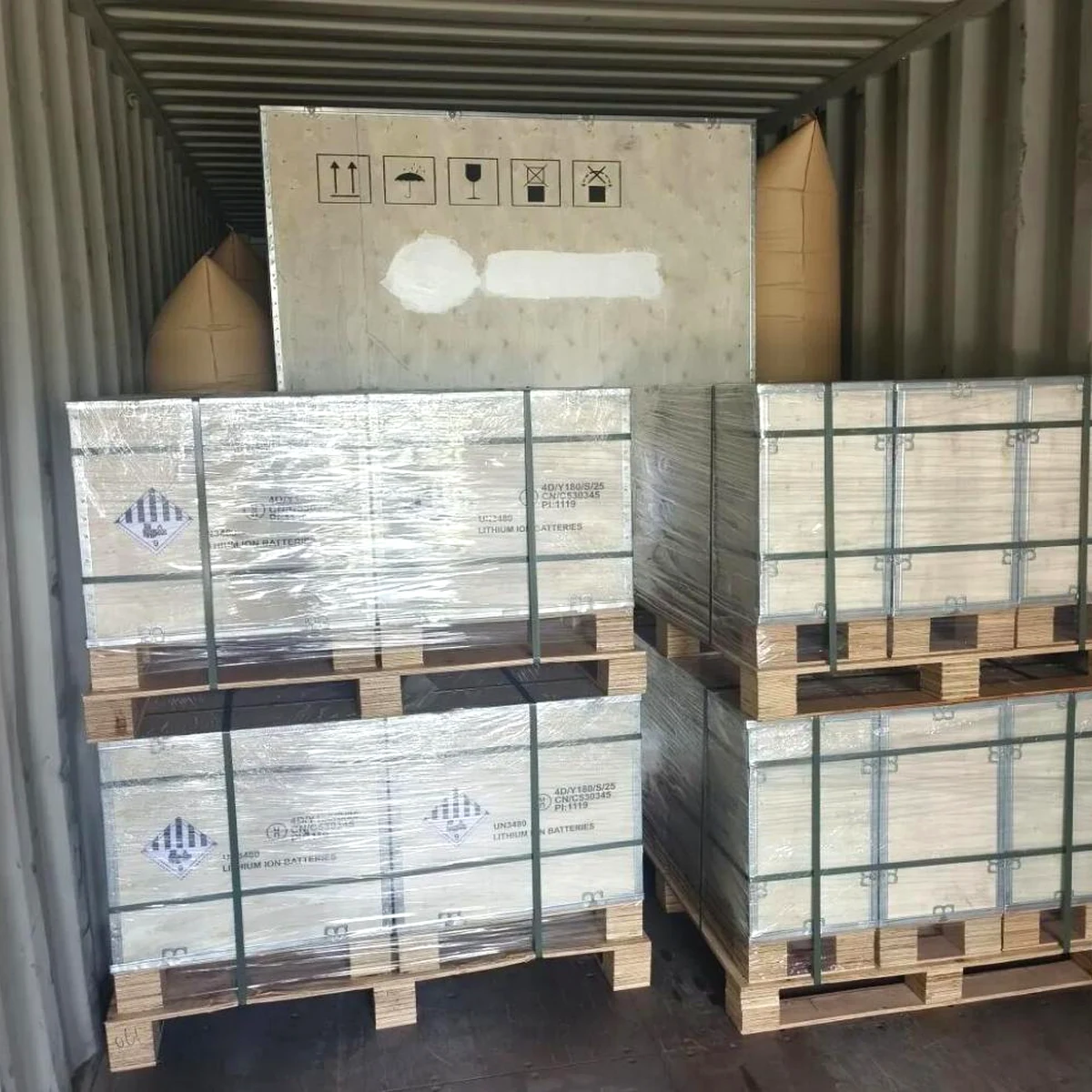 Crated and palletised energy storage equipment secured inside a shipping container